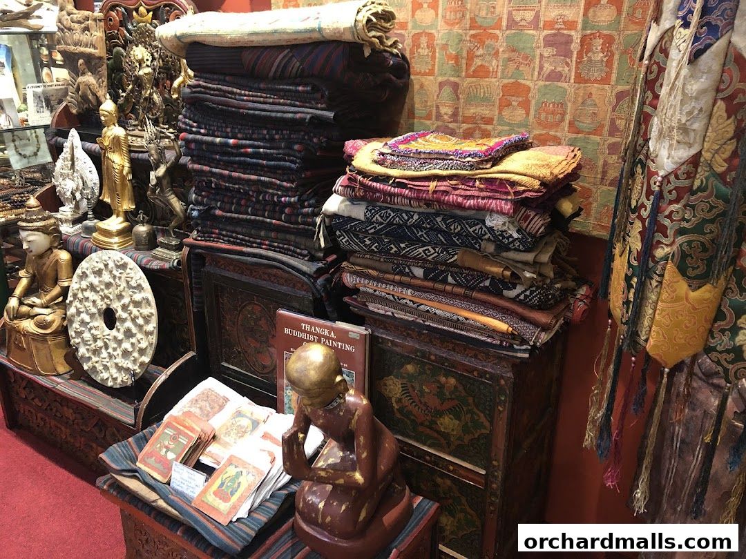 A collection of Tibetan Buddhist art, textiles, and statues displayed in a shop.
