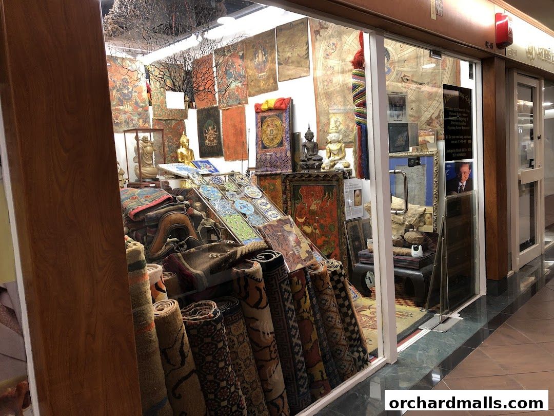 A shop displaying Tibetan artifacts, rugs, and statues through its glass storefront.