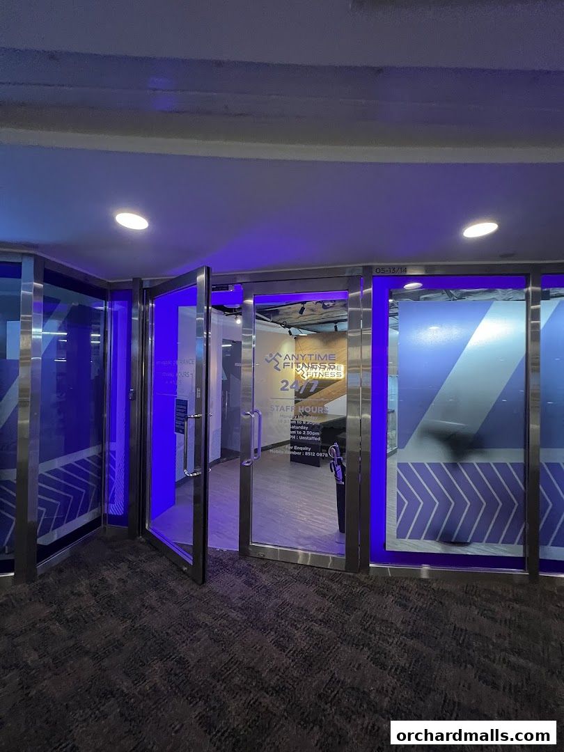 The entrance to Anytime Fitness Wheelock Place, featuring glass doors and blue lighting.