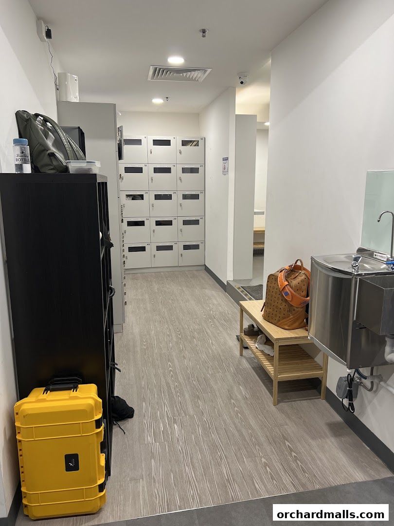 Interior view of a gym locker area with lockers, a water fountain, and storage.