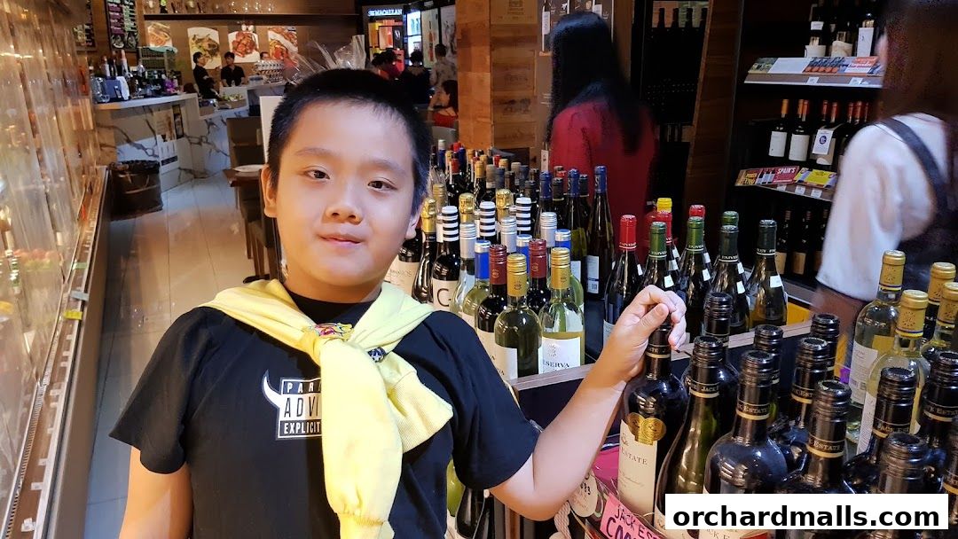 A young boy stands in front of a display of wine bottles at AP House.