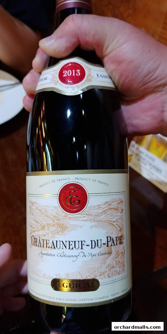 A hand holds a bottle of 2013 Chateauneuf-du-Pape wine from E. Guigal.