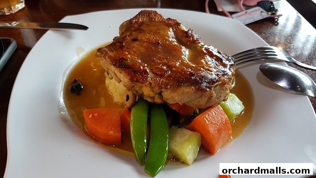 A delicious plate of chicken with mashed potatoes, carrots, and green beans in a savory sauce.