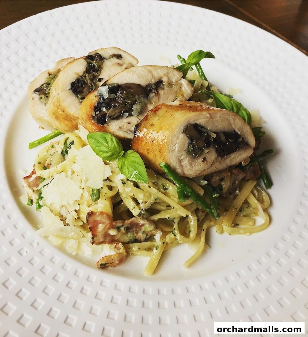 A plate of stuffed chicken roulade with pasta, green beans, and shaved parmesan cheese.
