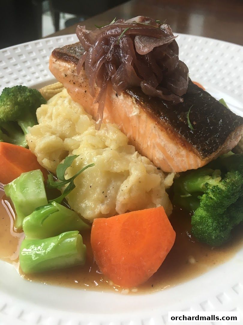 A delicious plate of pan-seared salmon with mashed potatoes and fresh vegetables.