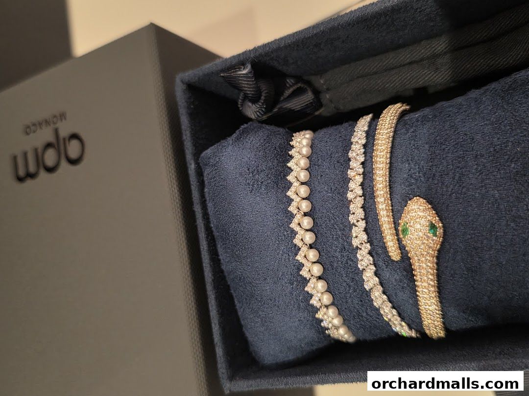 APM Monaco jewelry box showcasing pearl and diamond bracelets and a snake-shaped bracelet.