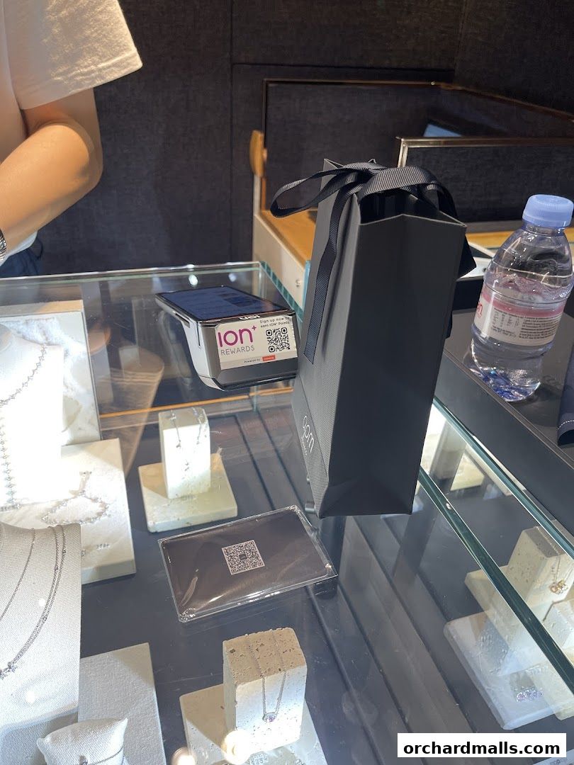 A jewelry store display case with necklaces, earrings, a shopping bag, and a payment terminal.