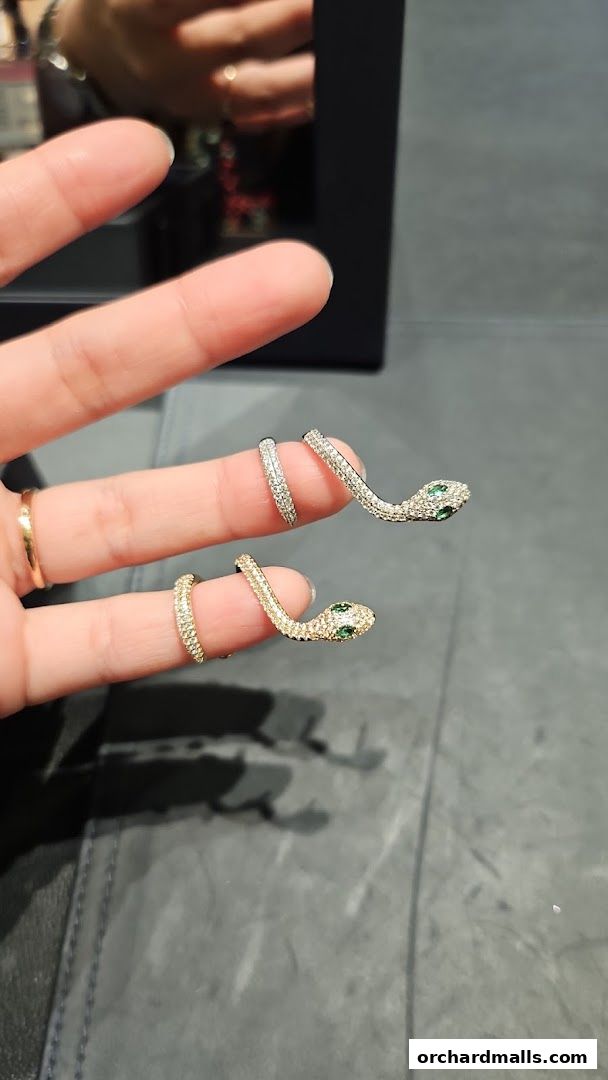 A person's fingers adorned with sparkling snake-shaped rings.
