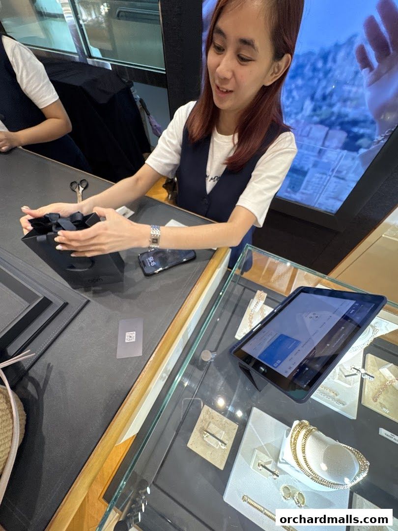 A sales associate presents a gift-wrapped box at APM Monaco Singapore ION Orchard.