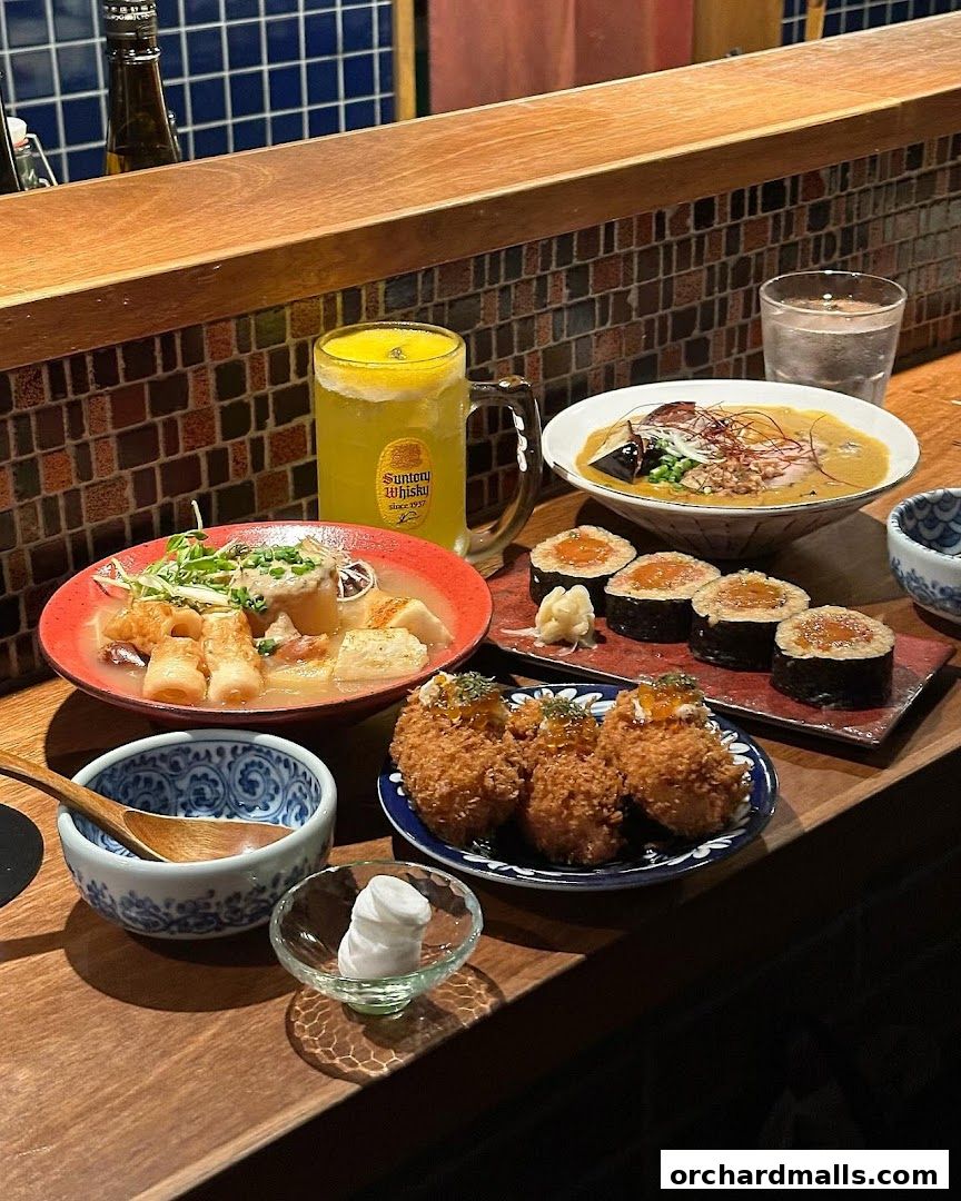 A spread of Japanese food including sushi, fried items, and a bowl of soup with a drink.