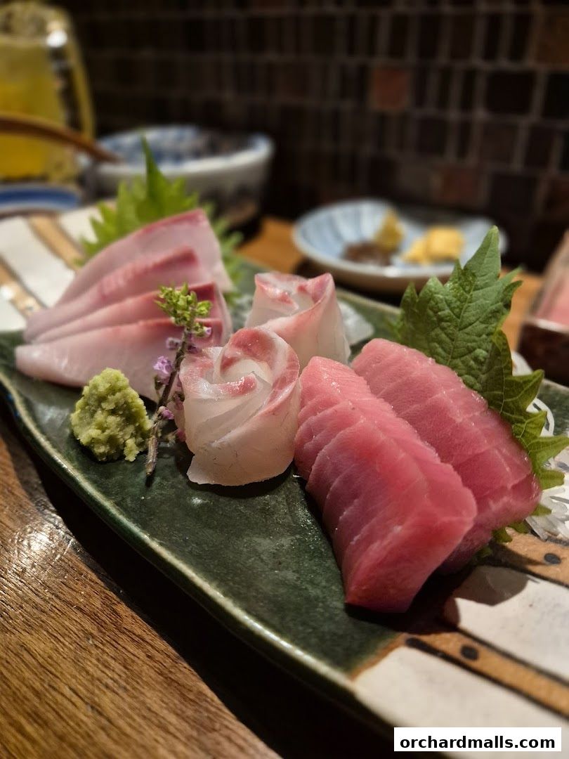 A platter of fresh sashimi, including tuna and white fish, served with wasabi.