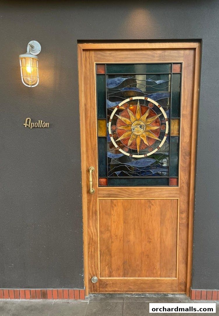 The entrance to Apollon features a wooden door with a stained-glass sun motif and a vintage light fixture.