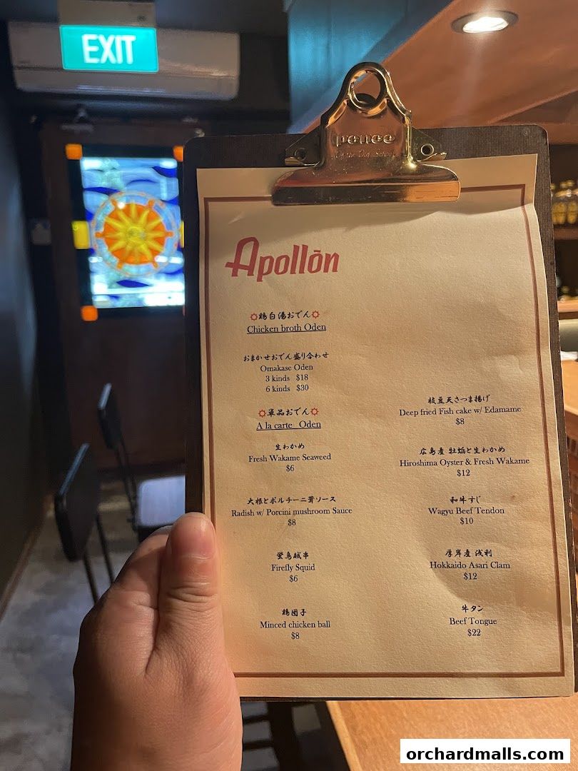 A hand holds a menu for Apollon, featuring Japanese dishes like Oden and seafood.
