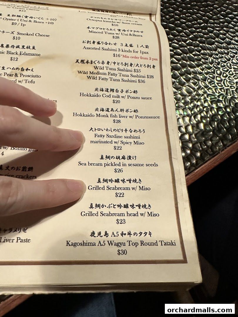 A close-up of a Japanese restaurant menu with various seafood and meat dishes listed.