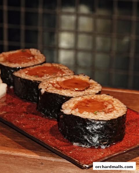 Four pieces of sushi rolls with rice and nori on a red plate.