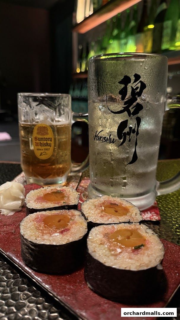 Close-up of sushi rolls and two glasses of drinks, one with beer and the other with a clear beverage.