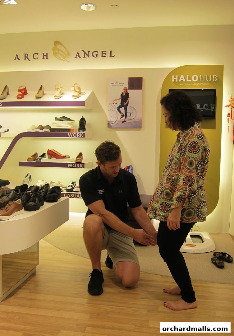 A shoe consultant measures a customer's foot in a well-lit shoe store.