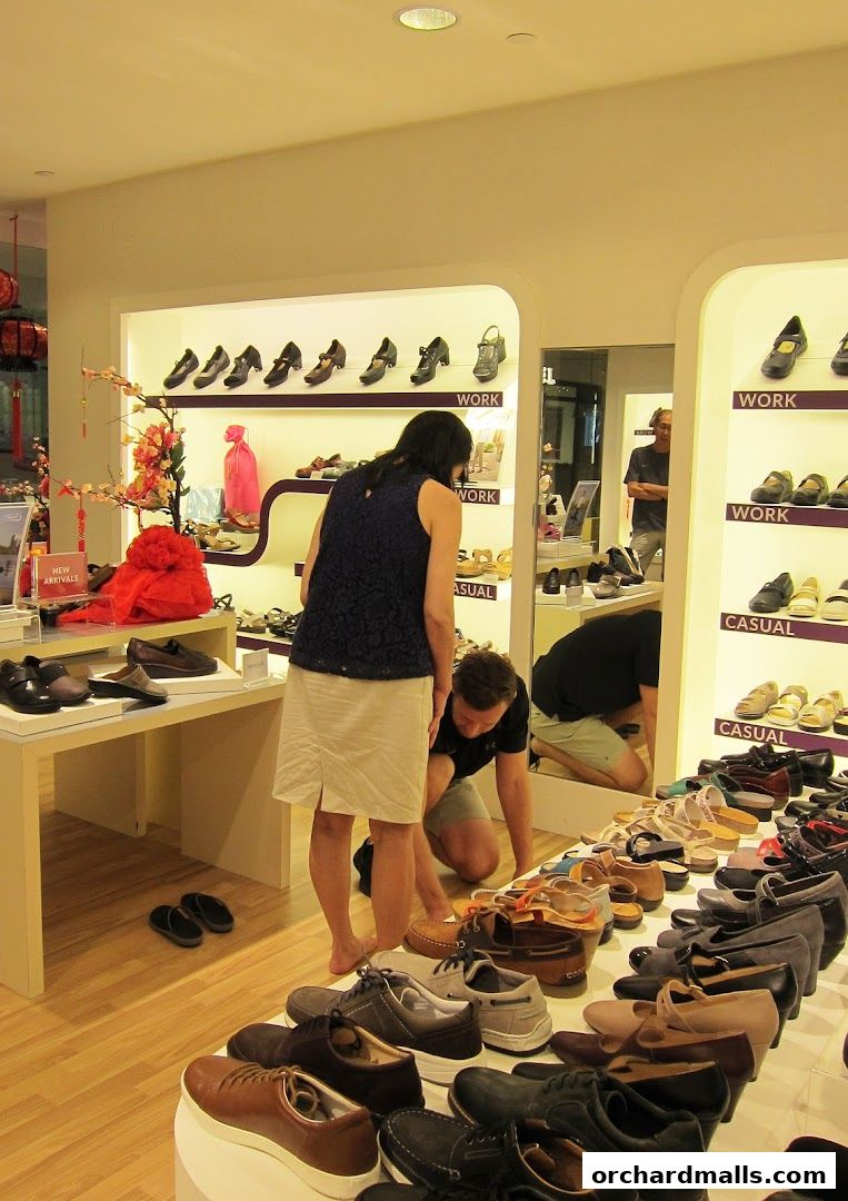 Customers browsing shoes in a well-lit retail store with display shelves.