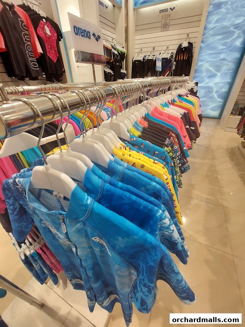 A display of colorful swimwear and rash guards hanging on racks inside a retail store.