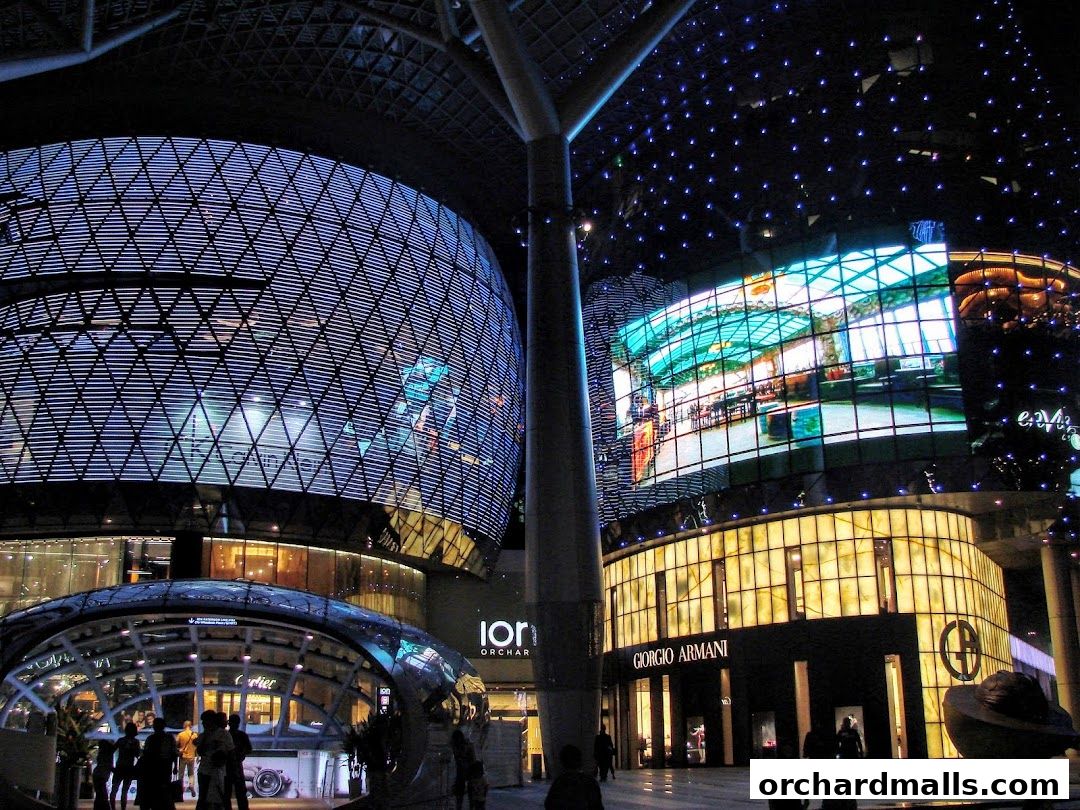 The Giorgio Armani store front at night, illuminated with warm lighting and a large digital display above.