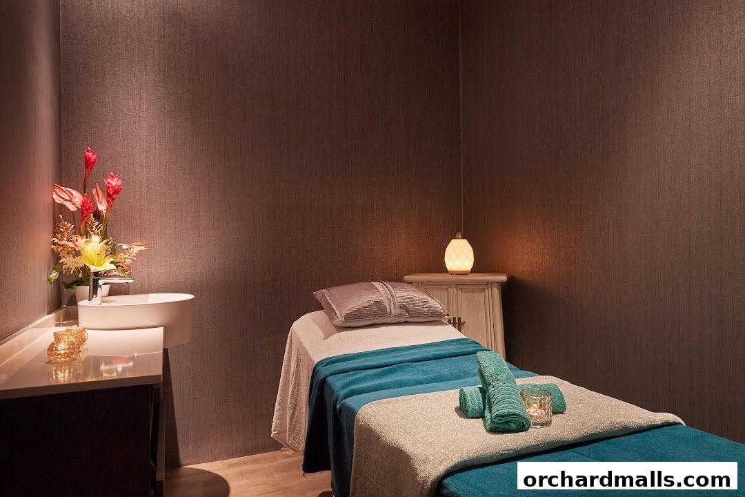 A tranquil spa room with a massage bed, sink, and decorative flowers.