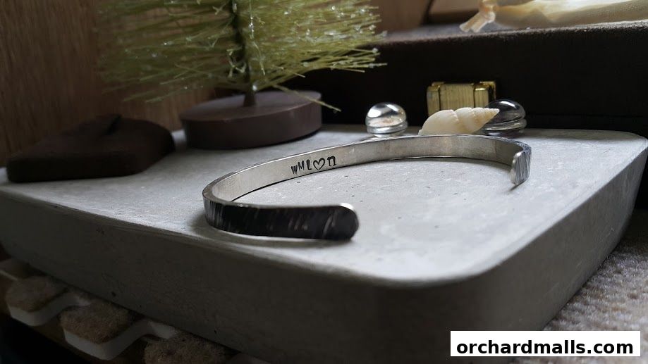 A close-up of a handcrafted metal bracelet with personalized engraving.
