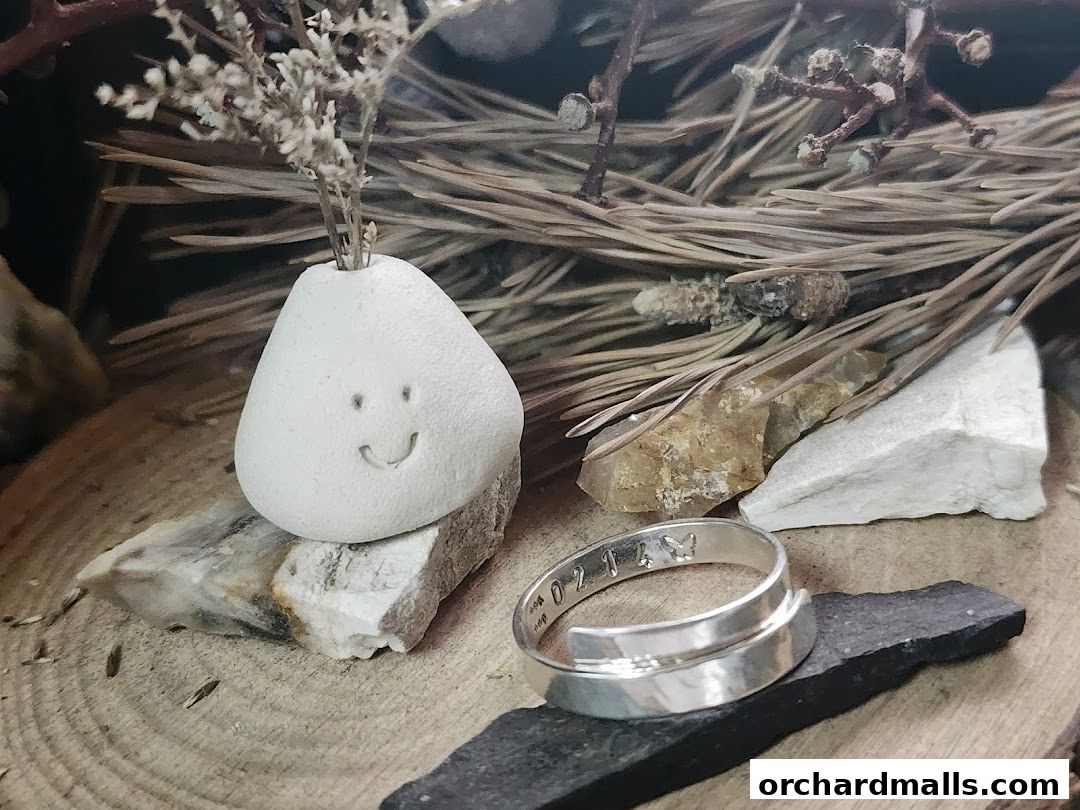 A whimsical stone with a smiley face and a silver ring with engraved numbers and a butterfly.