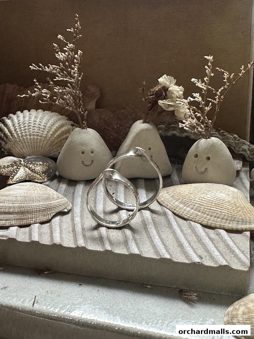 Artisan jewelry displayed with seashells and whimsical stone figures.