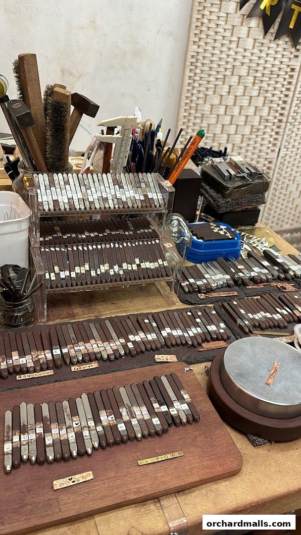 A workbench with various metal stamping tools and supplies for jewelry making.