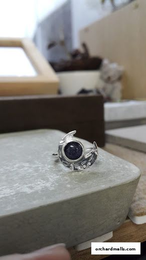 A close-up of a crescent moon-shaped ring with a dark blue stone.