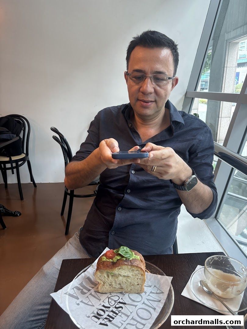Man taking a photo of avocado toast and coffee at ASTRA Deli.