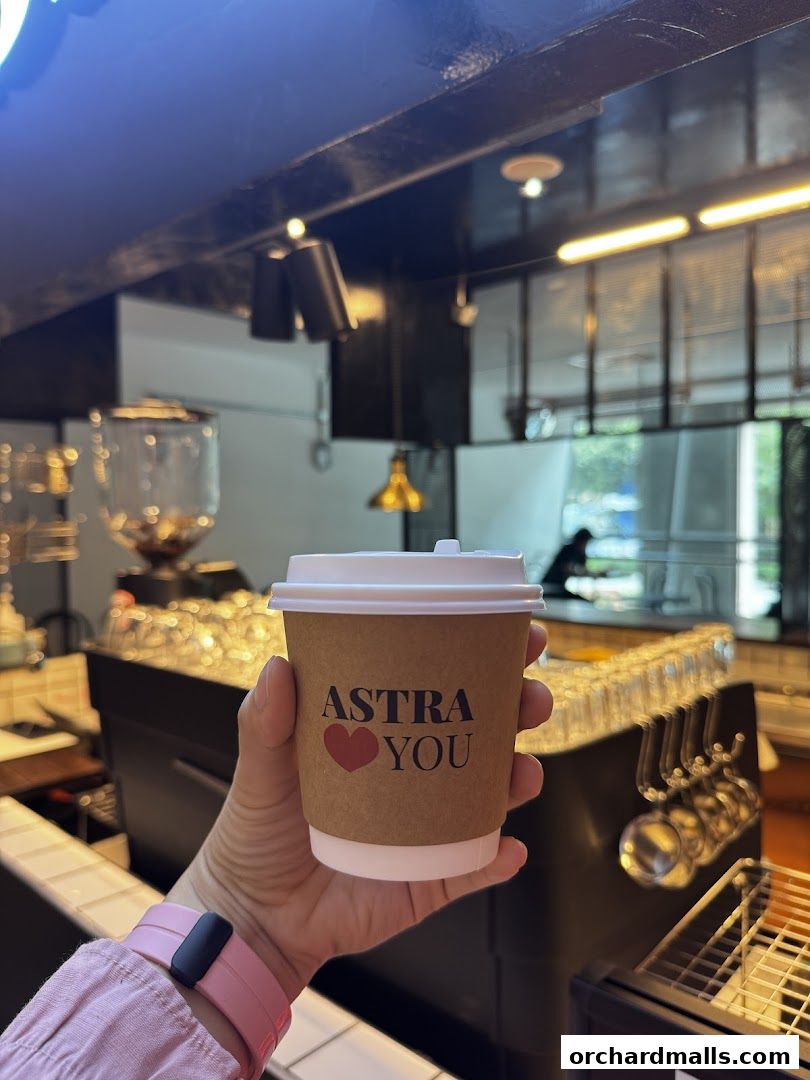 A hand holds a coffee cup with the logo 'ASTRA YOU' and a heart.