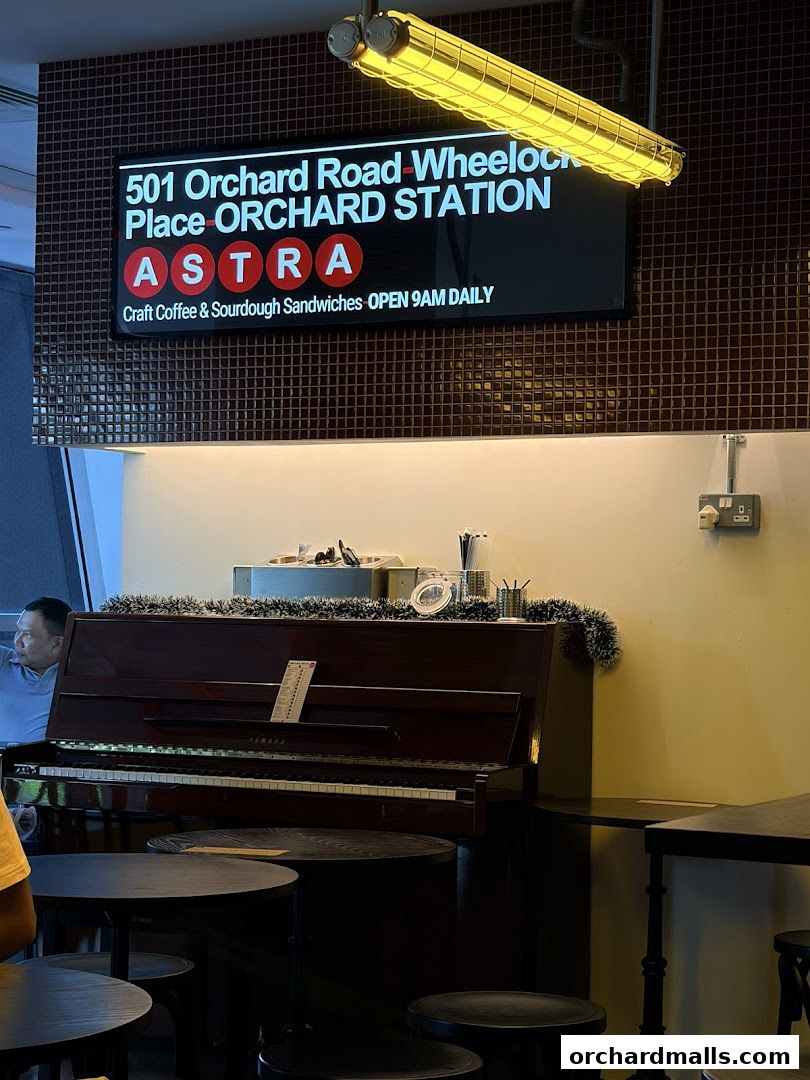 A piano sits in front of a sign for ASTRA Deli, offering craft coffee and sourdough sandwiches.