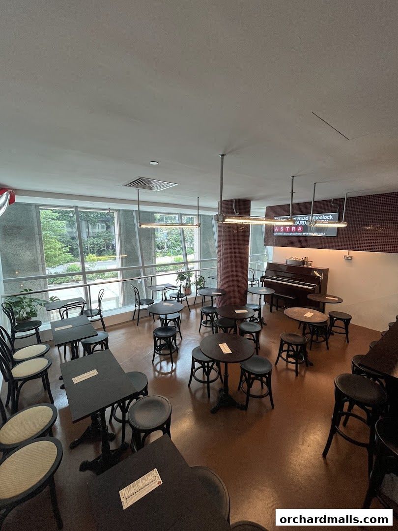 Interior of ASTRA Deli with tables, chairs, and a piano.