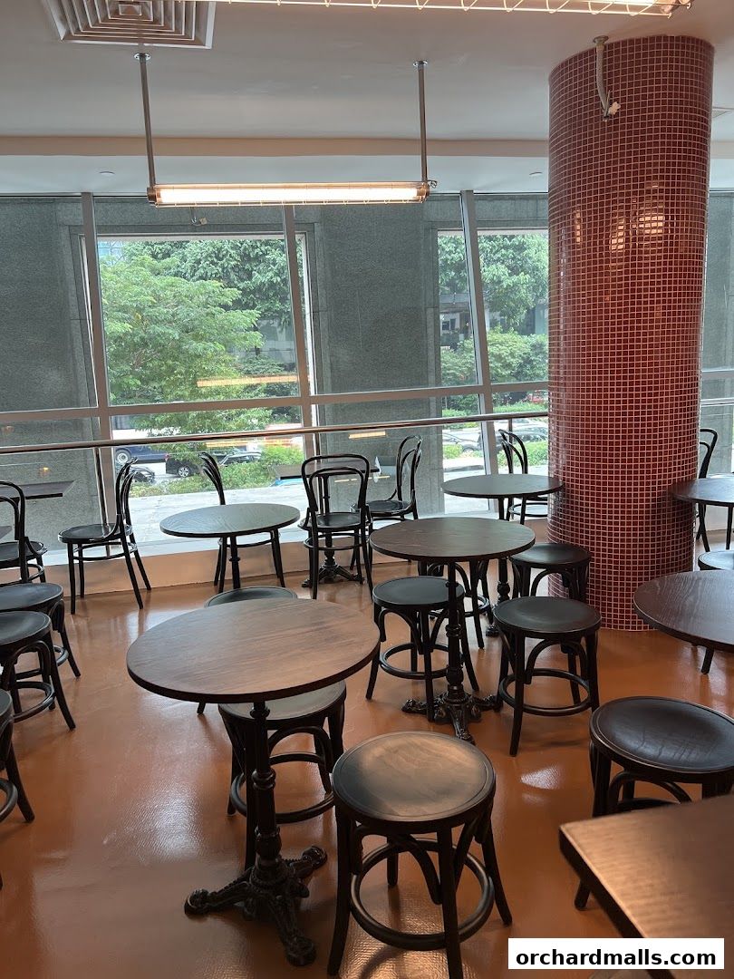 Interior shot of ASTRA Deli 星辰咖啡 showing tables and chairs with large windows.