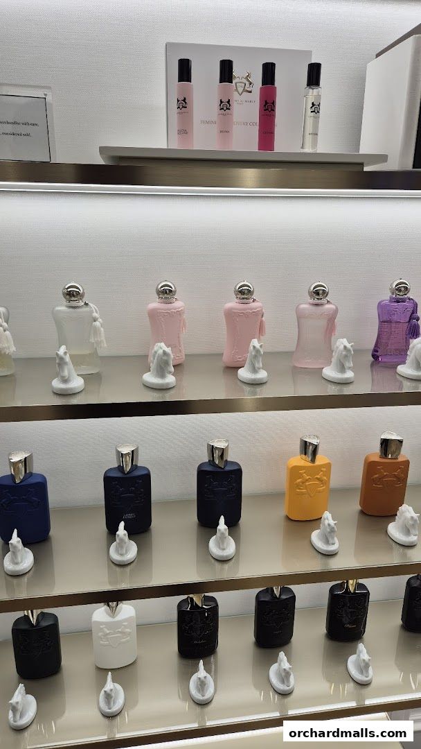 A display of various designer perfume bottles on shelves, featuring brands like Atelier Cologne, Ex Nihilo, Parfums De Marly Paris, and Roja.