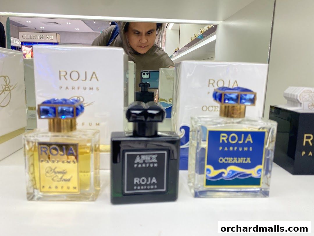 A display of luxury Roja perfumes with ornate blue caps and elegant packaging.