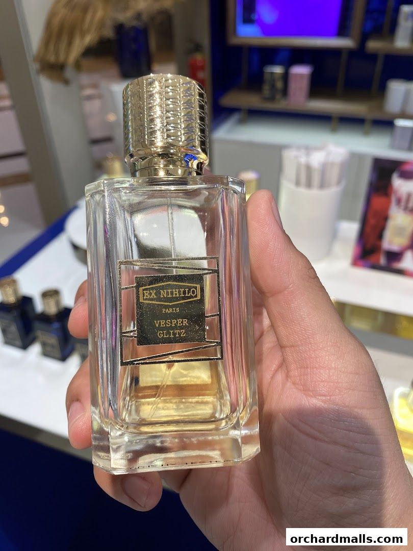 A hand holds a bottle of Ex Nihilo Vesper Glitz perfume in a luxury fragrance store.