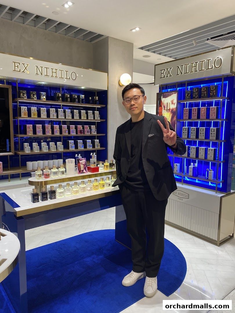 A man stands in a perfume shop displaying various fragrances from Ex Nihilo.