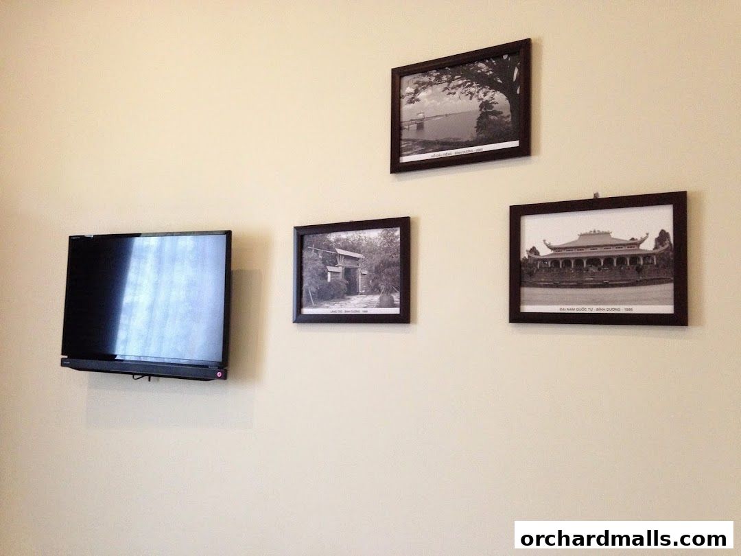 A flat-screen TV and three framed black and white photographs on a cream-colored wall.