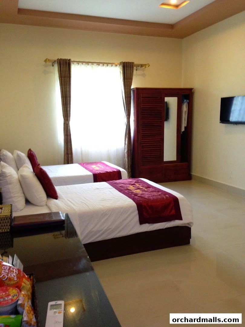 A hotel room with two beds, a wardrobe, and a television.