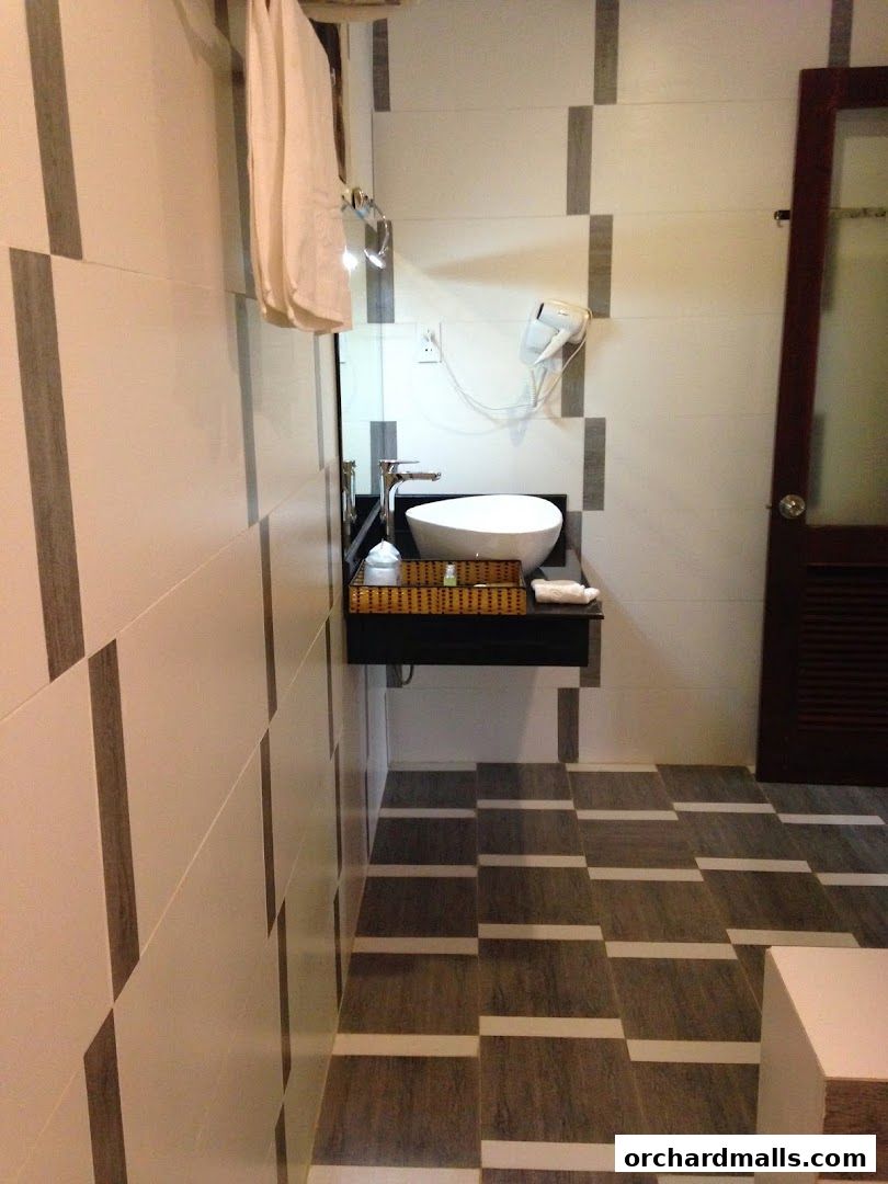 A modern bathroom with a vessel sink, hairdryer, and stylish tiled walls and floor.