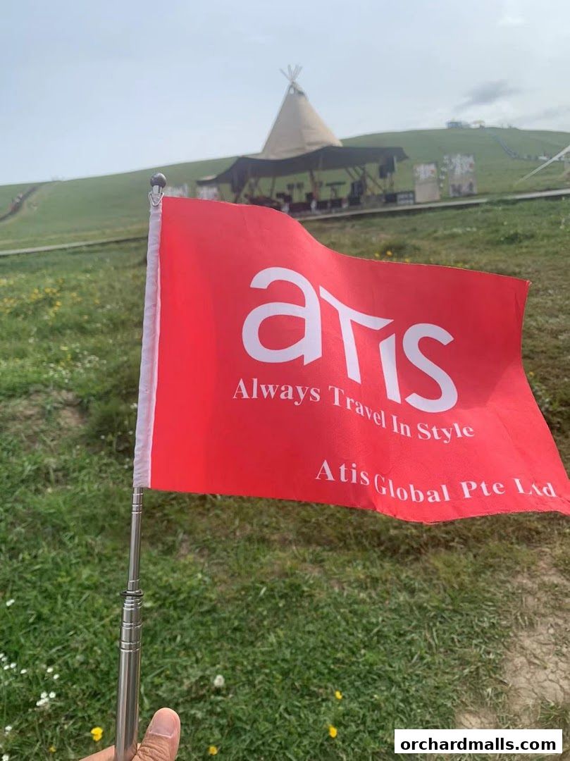 A red flag with 'atis' logo and slogan 'Always Travel In Style' held by a hand.