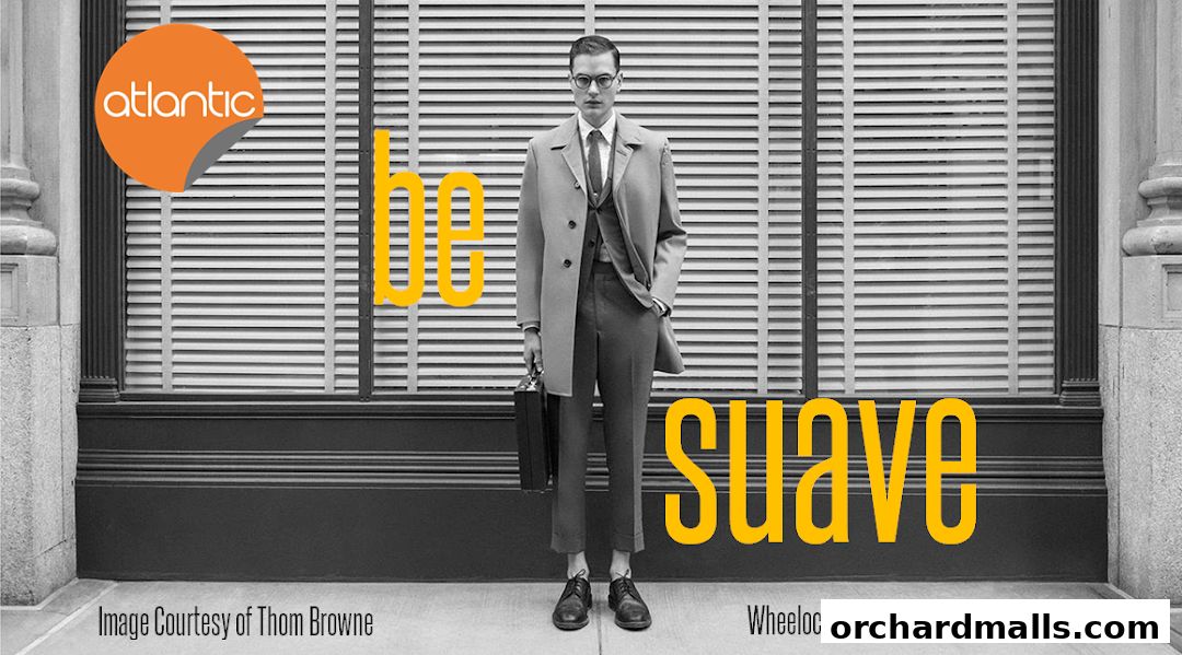 A man in a suit and trench coat stands in front of a building with the words 'be suave' and 'atlantic' visible.