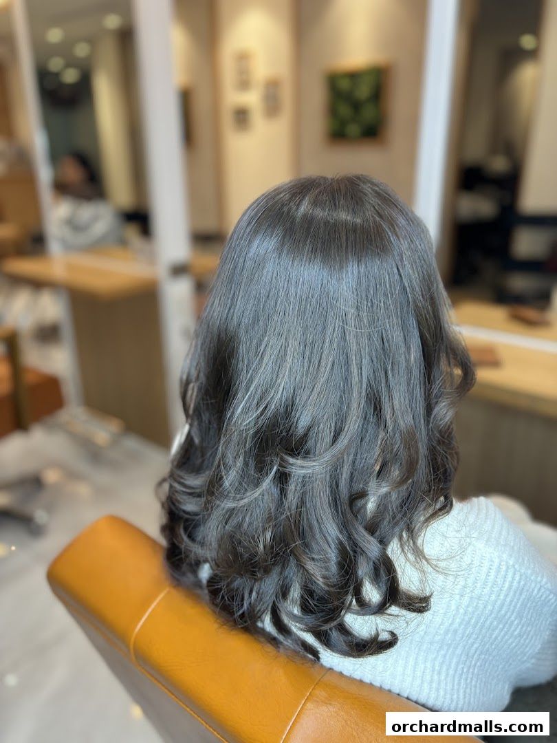 A woman's styled dark hair with subtle highlights, viewed from behind in a salon.