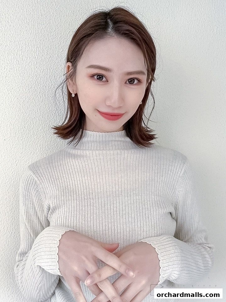 A woman with a stylish bob haircut and subtle makeup smiles gently.