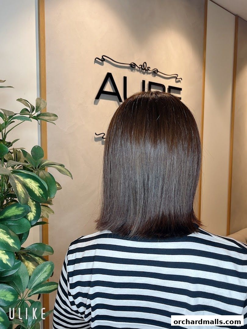 A person with a fresh haircut stands in front of the AUBE Beauty Salon Wheelock Place logo.