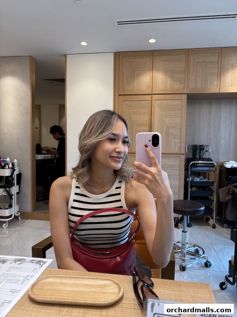 A woman takes a selfie in a beauty salon, showcasing her hairstyle and the salon's interior.