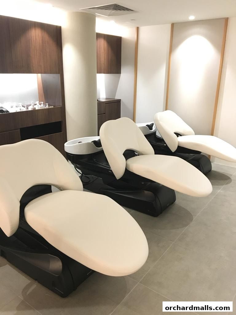 Interior view of a modern beauty salon with comfortable reclining chairs and sinks.
