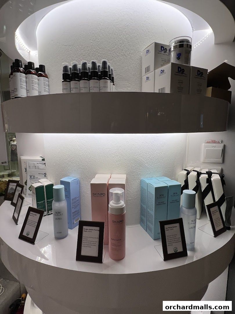 A display of various skincare products, including bottles, boxes, and jars, on a curved shelf.